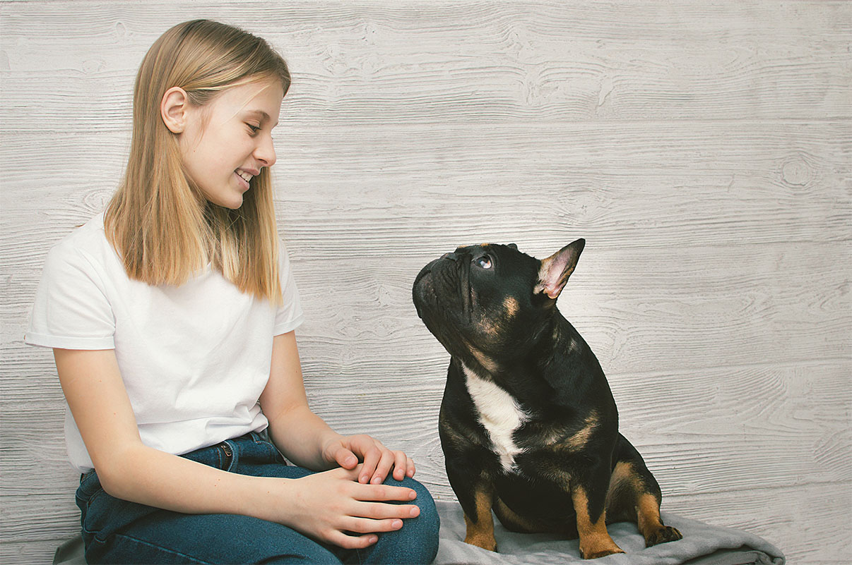girl and dog look at each other against wood panel background; why dogs stare